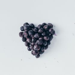Heart shape made of frozen blueberries on light background