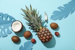 Set of tropical fruit and paper tropical leaves on blue background, top view