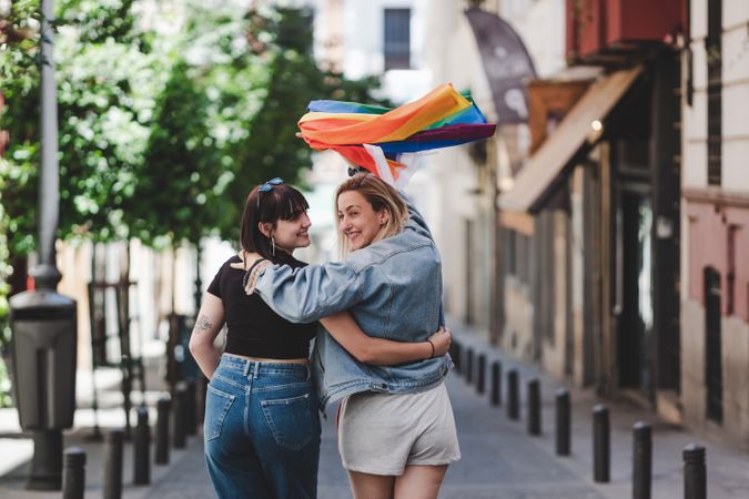 Lesbian couple with LGBT flag walking on street