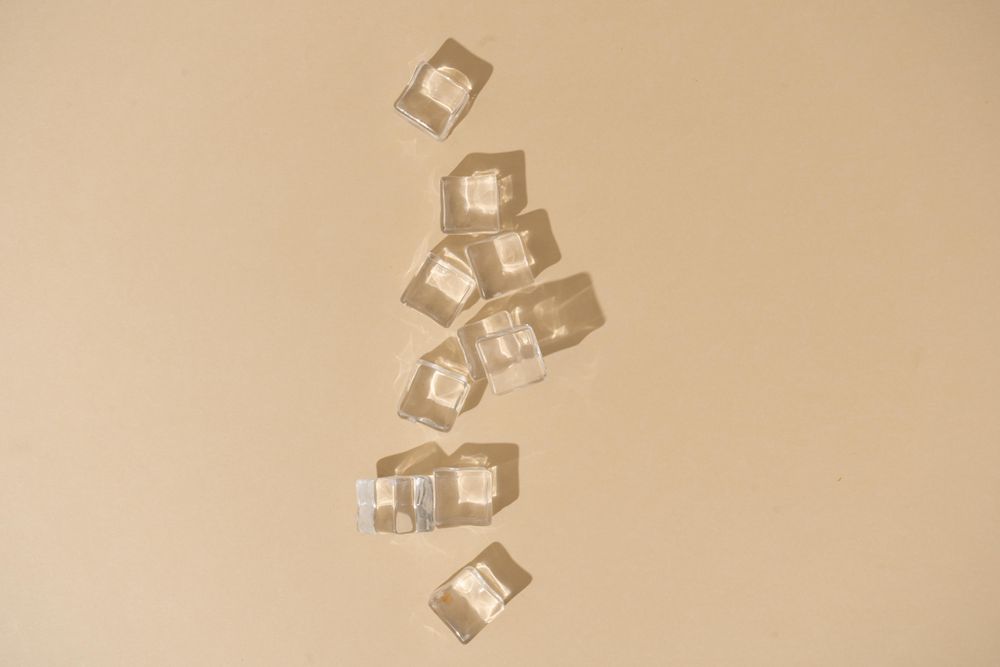 Flat lay of ice cubes on beige background with shadows