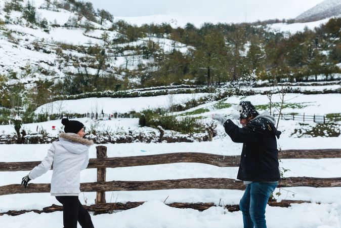Couple having fun with snow in rural landscape