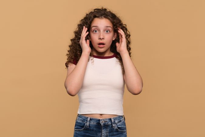 Young girl with hands on temples, showing surprise