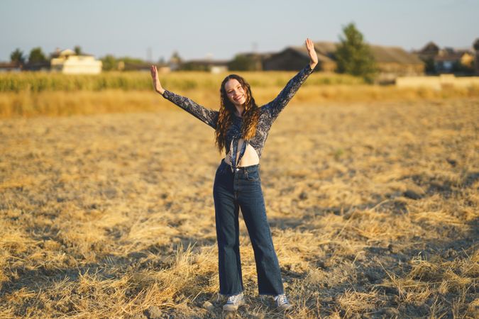 A Joyful Young Woman Dancing Happily in a Brightly Sunlit Field on a Beautiful Day