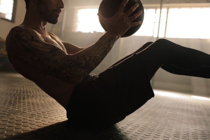 Muscular man exercising with medicine ball at gym