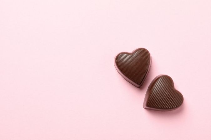 Chocolate candies in the heart form on pink background