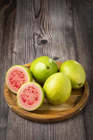 Fresh sliced guavas on wooden table.