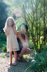 Mother and daughter snack on edible plants in garden with sun rays