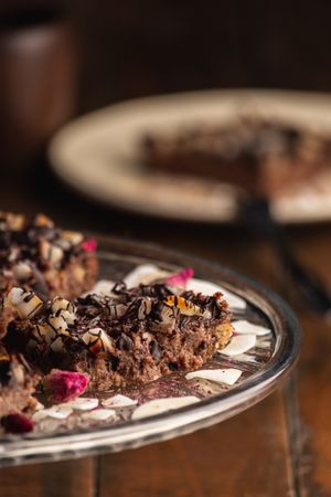 Tasty brown cake decorated with flakes on glass plate