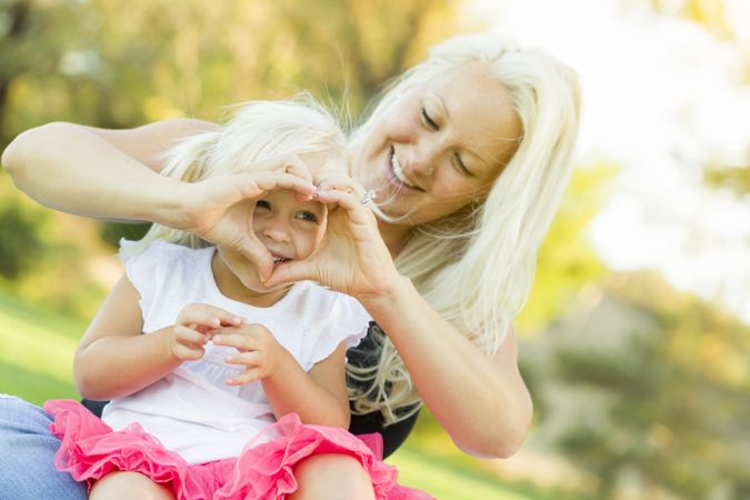 Little Girl With Mother Making Heart Shape with Hands