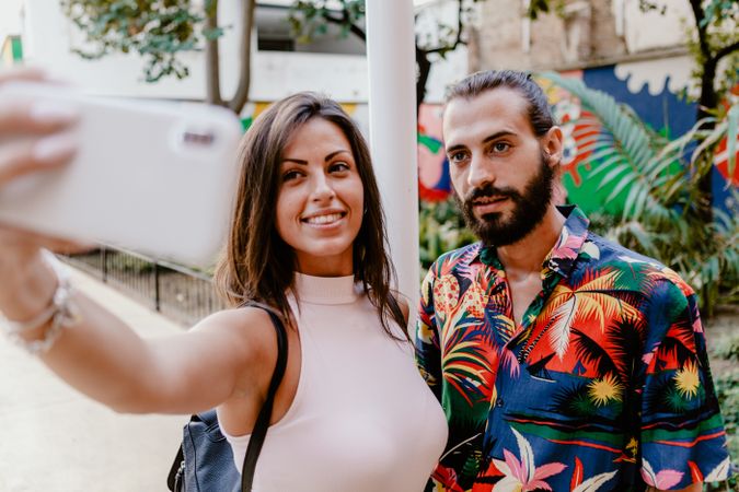 Trendy couple taking selfie on city street