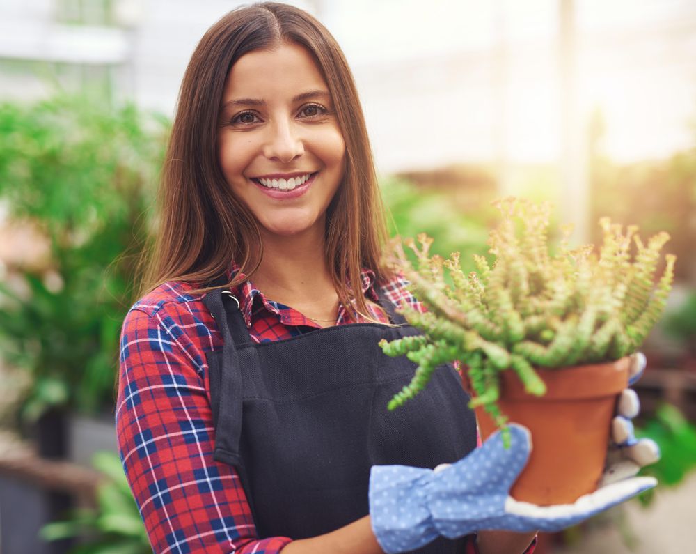 Woman holding terra-cotta planter in a greenhouse