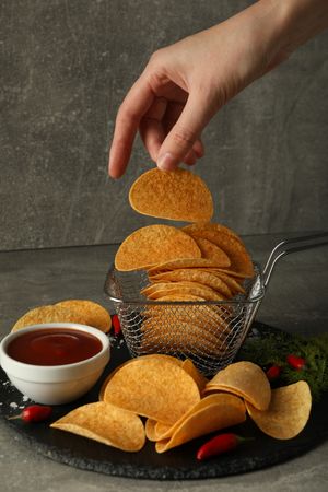 Potato chips with sauce and chili pepper on a dark background
