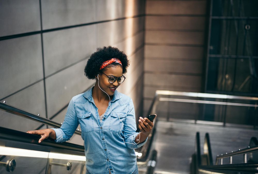 Woman smiling looking at phone on escalator