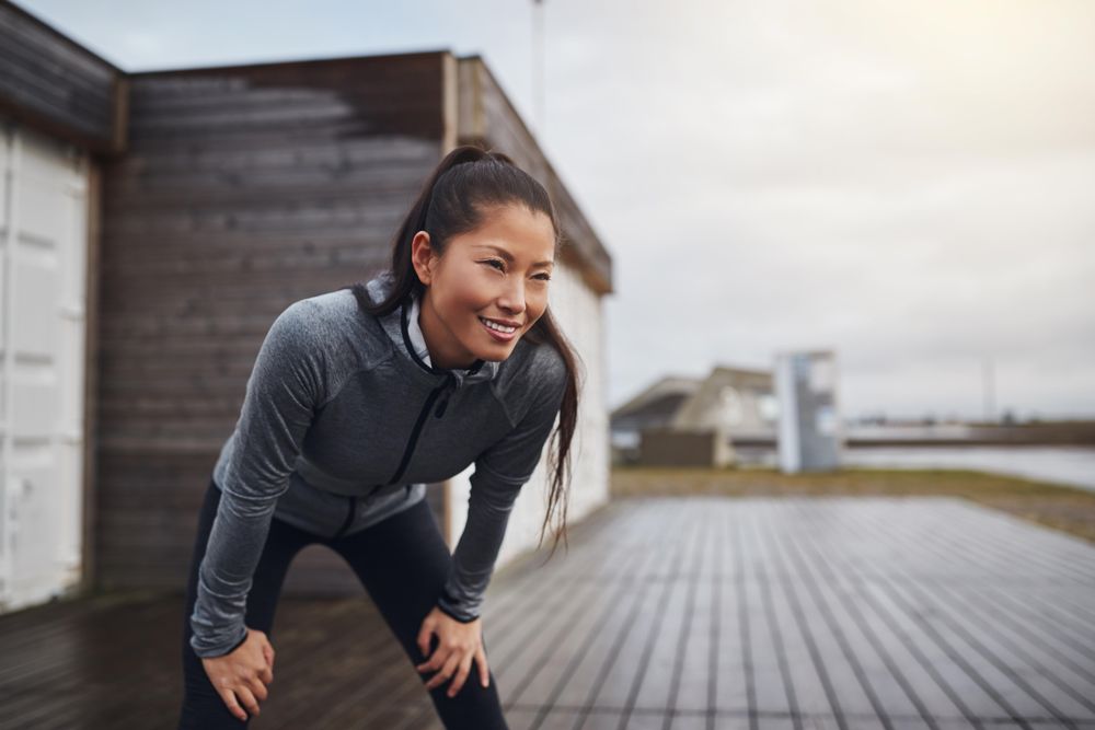Happy woman leaning down with hands on knees after a run