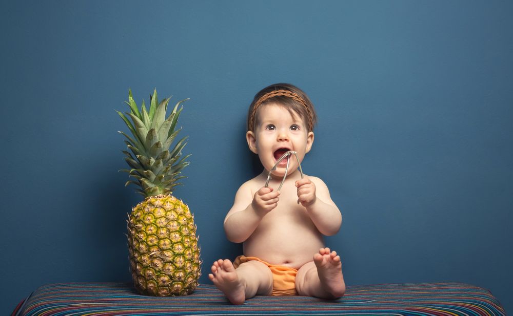 Happy baby playing with a pineapple