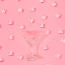 Martini glass with ice cubes pattern on pastel pink background