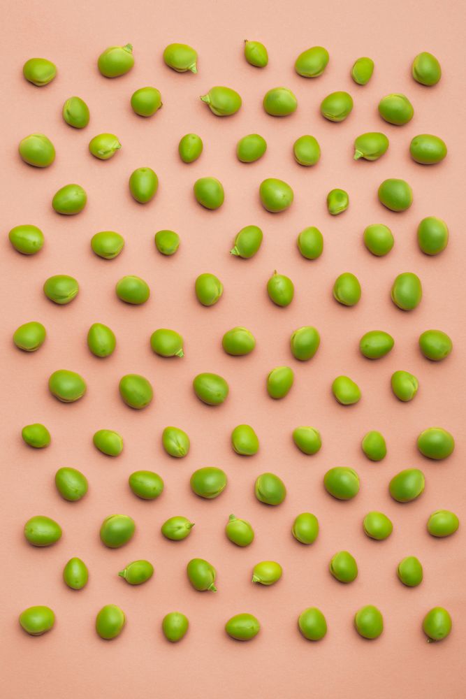 Set of peas placed orderly on salmon colored background