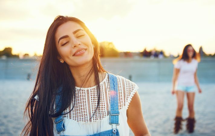 Portrait of calm brunette woman with friends in background on beach