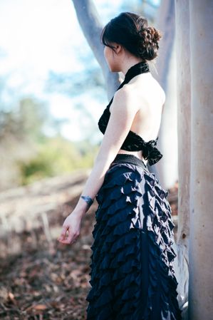 Side view of woman with long skirt and cropped top looking at nature