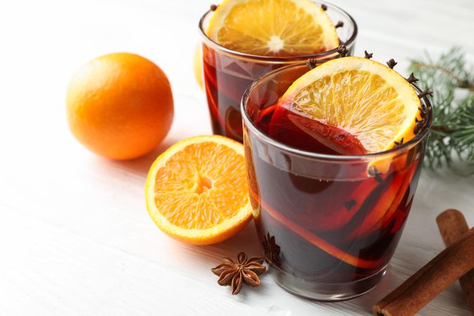 Glasses of tasty mulled wine with orange on wooden background, close up