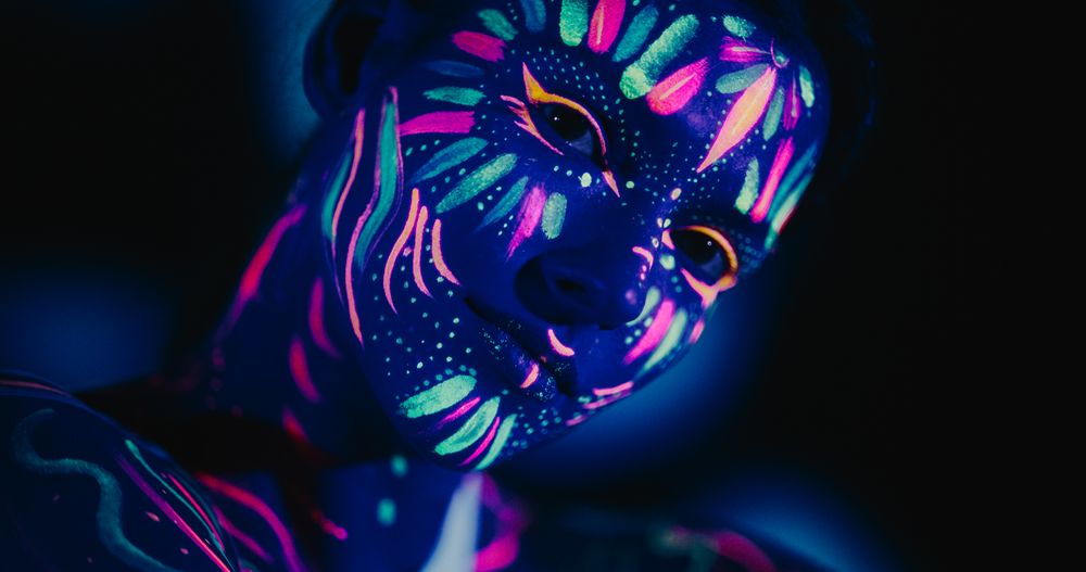 Captivating Beauty Shoot: Young Female Model with Neon Body Art Paint and Red Abstract Background
