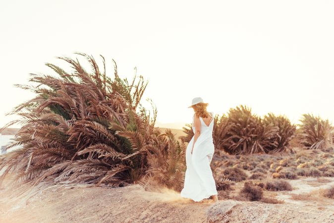 Woman in white dress in dry field in sunlight