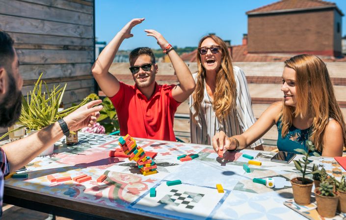 Group of friends laughing while young man lose in game in a rooftop party