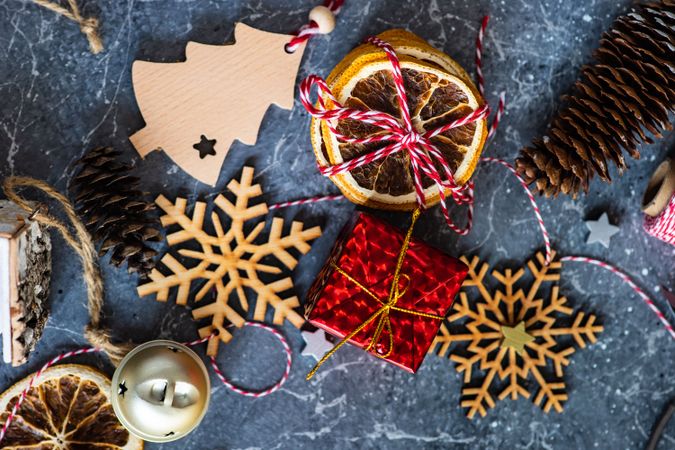 Wooden snowflakes and tree ornaments with dried orange slices and pine cones on marble table