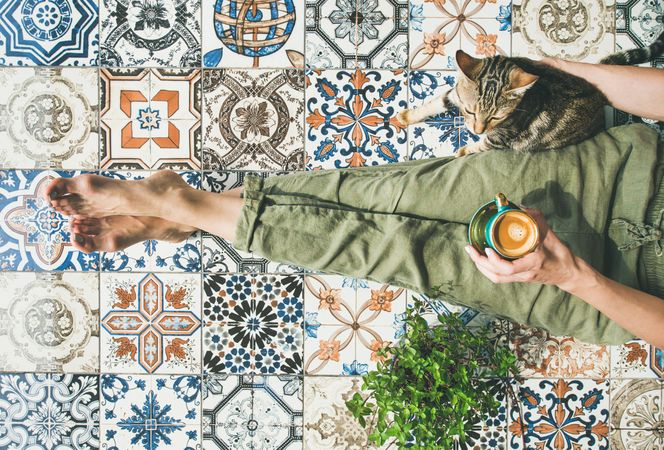 Woman on tiled terrace with coffee and cat