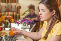 Pregnant mother working in home office with son