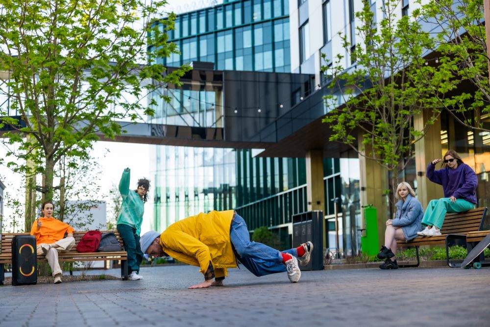 Young Stylish B-boy Breakdancing On City Street Among Buildings In Urban Area.