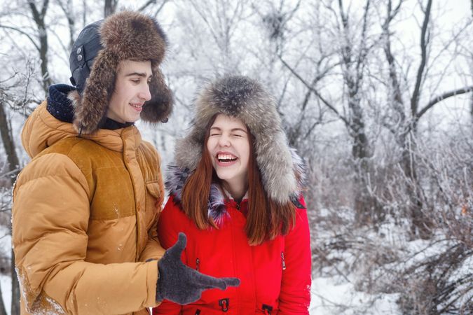 Teenage couple laughing in wintery forest