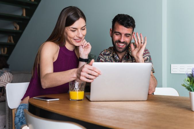 Cheerful couple using laptop in living room