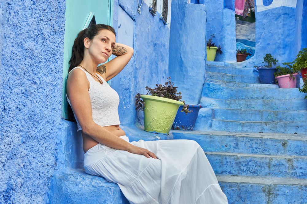 Pensive woman sitting on steps between ancient buildings