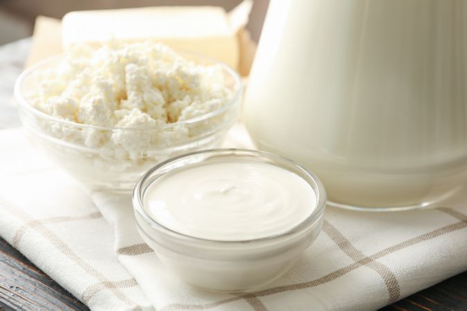 Fresh dairy products and towel on wooden background, close up