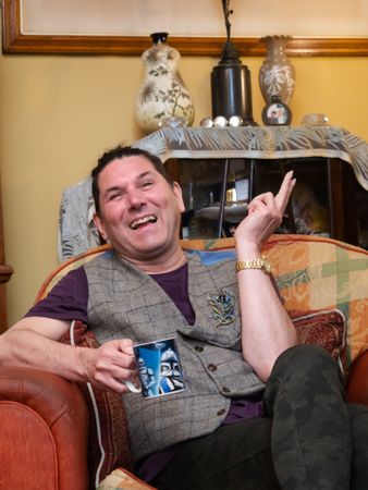 Man smiling at home drinking from mug on stylish sofa