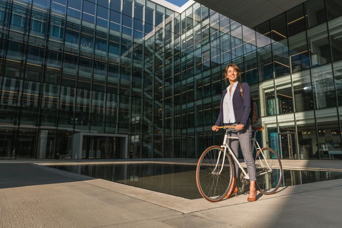 Cheerful businesswoman riding bicycle on street