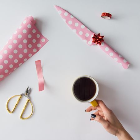 DIY gift wrapped knife in pink paper on table with coffee cup