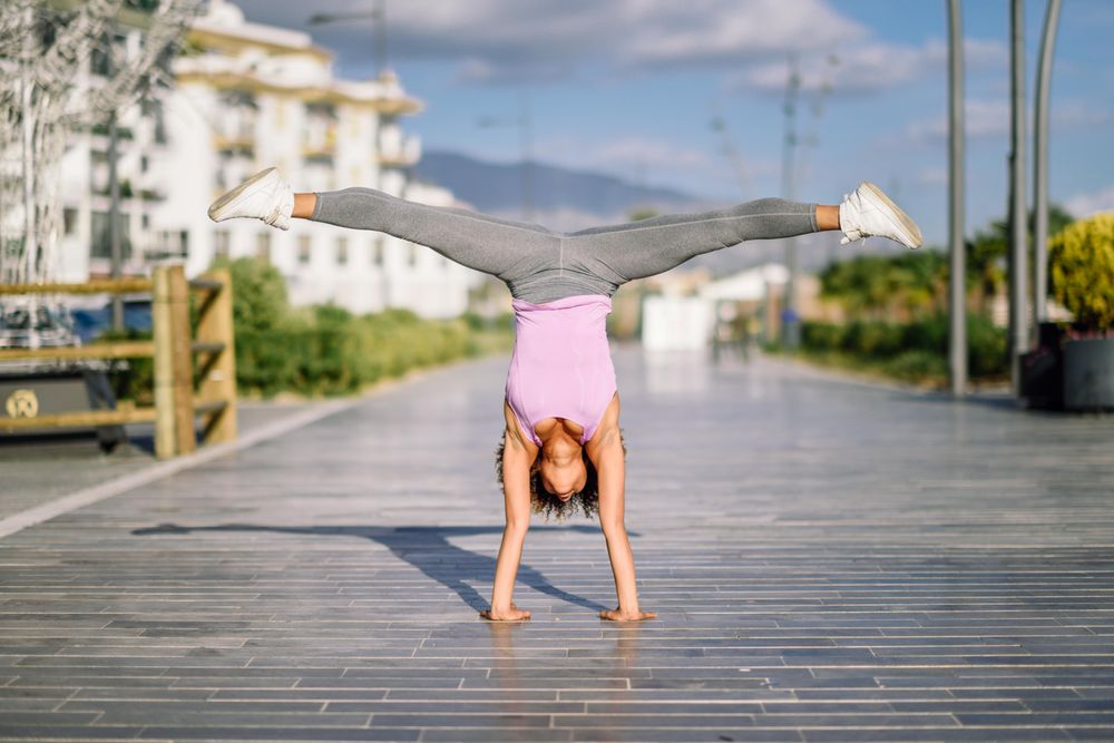 Woman in one handed handstand outside
