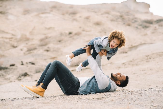 Black father playing with child on ground