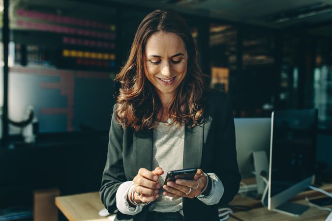 Businesswoman reading text on mobile phone in office