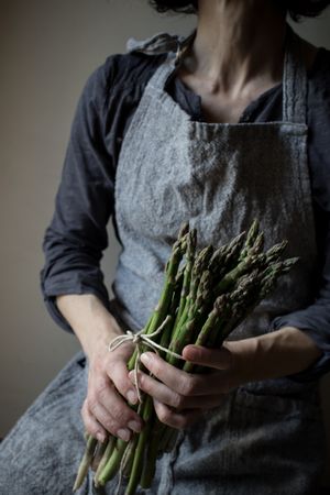 Faceless woman holding bundle of green asparagus
