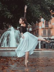 Gracious ballerina performing arabesque position in park