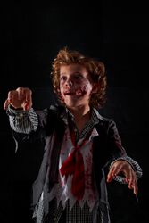 Vertical photo of a child disguised as a zombie with blood and glitter with arms raised walking