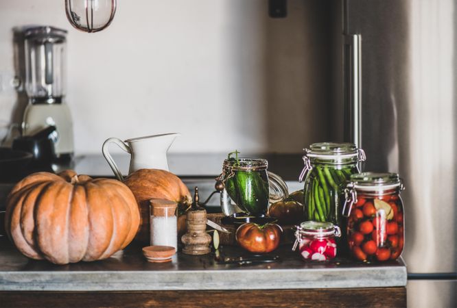 Rustic kitchen with pickled vegetables, spices and herbs on counter