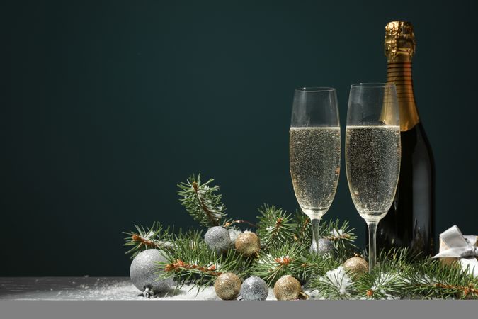 Champagne glasses and bottle on decorated background, space for text