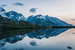Car on mountain shore with crystal lake reflecting cloudy sky