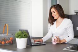 Smiling woman browsing on laptop and sitting on settee