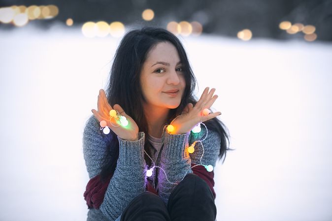 Smiling brunette woman holding string lights