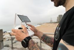 Sideview of man with remote for drone on wooden boardwalk on beach